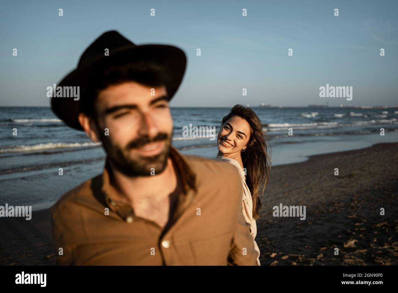 Girlfriend smiling while looking at boyfriend during sunset Stock Photo