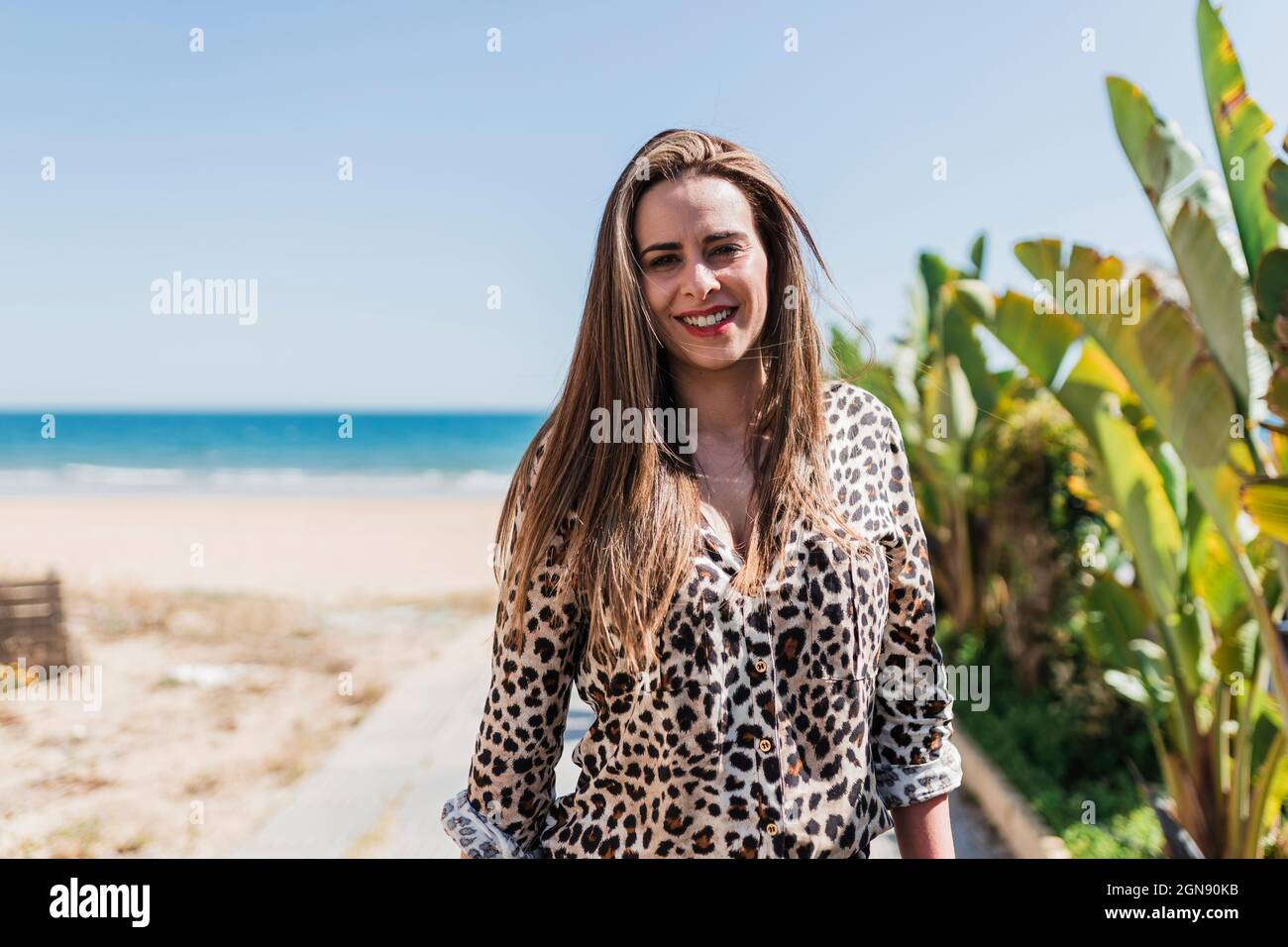 Smiling woman standing at beach during sunny day Stock Photo