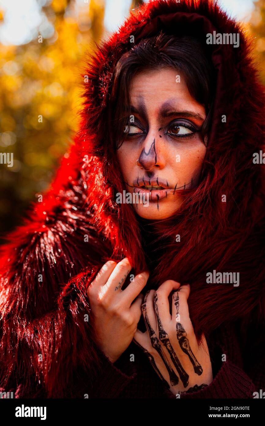Young woman covering head with fur jacket in forest Stock Photo