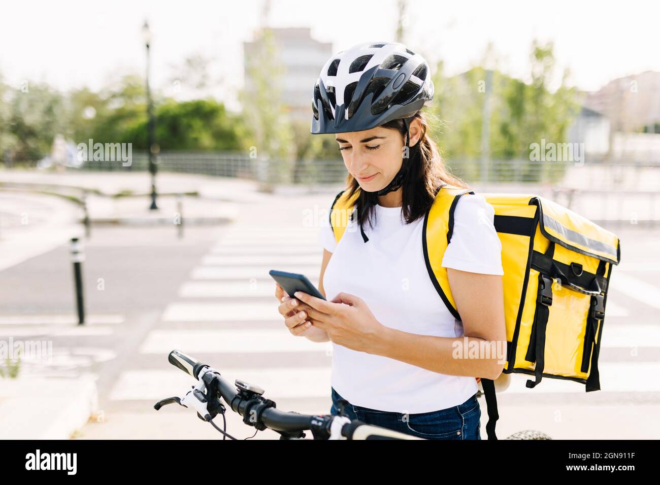 Delivery woman using mobile phone while standing on road Stock Photo