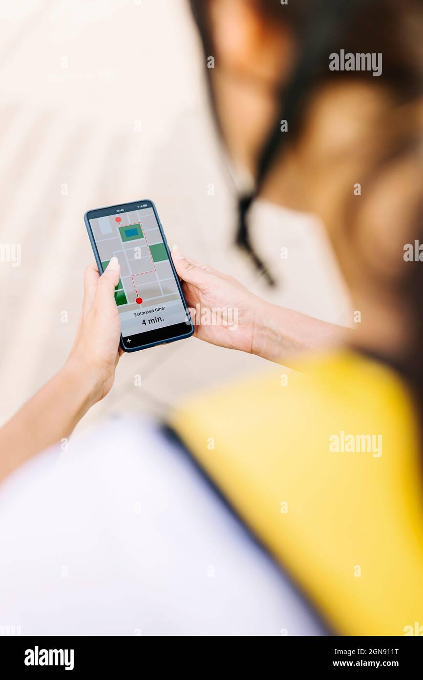 Female delivery person checking map on mobile phone Stock Photo