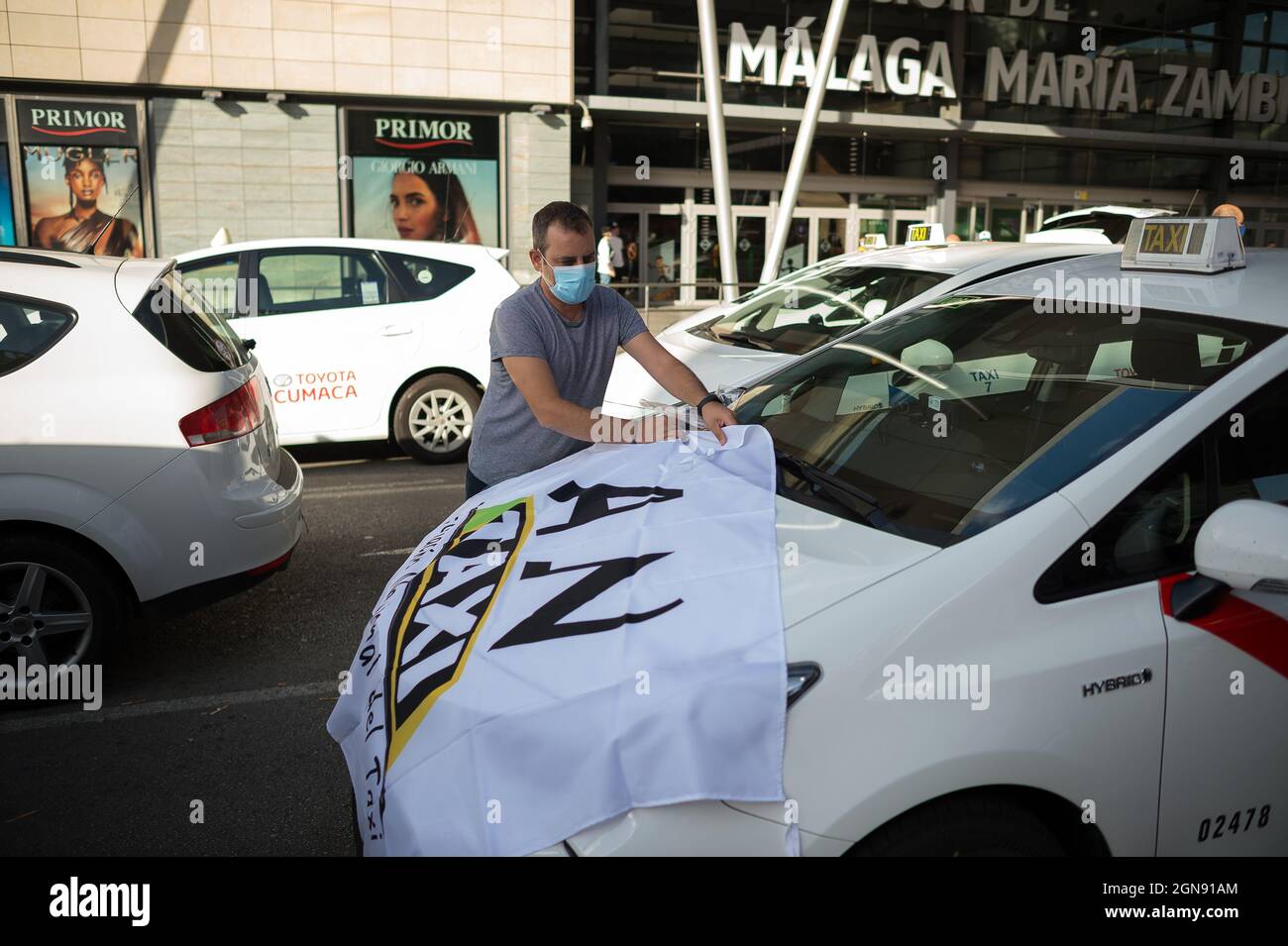Malaga, Spain. 23rd Sep, 2021. A taxi driver seen placing a flag on his taxi  as he takes part in the protest.Taxi drivers have marched and blocked main  streets in Malaga demanding