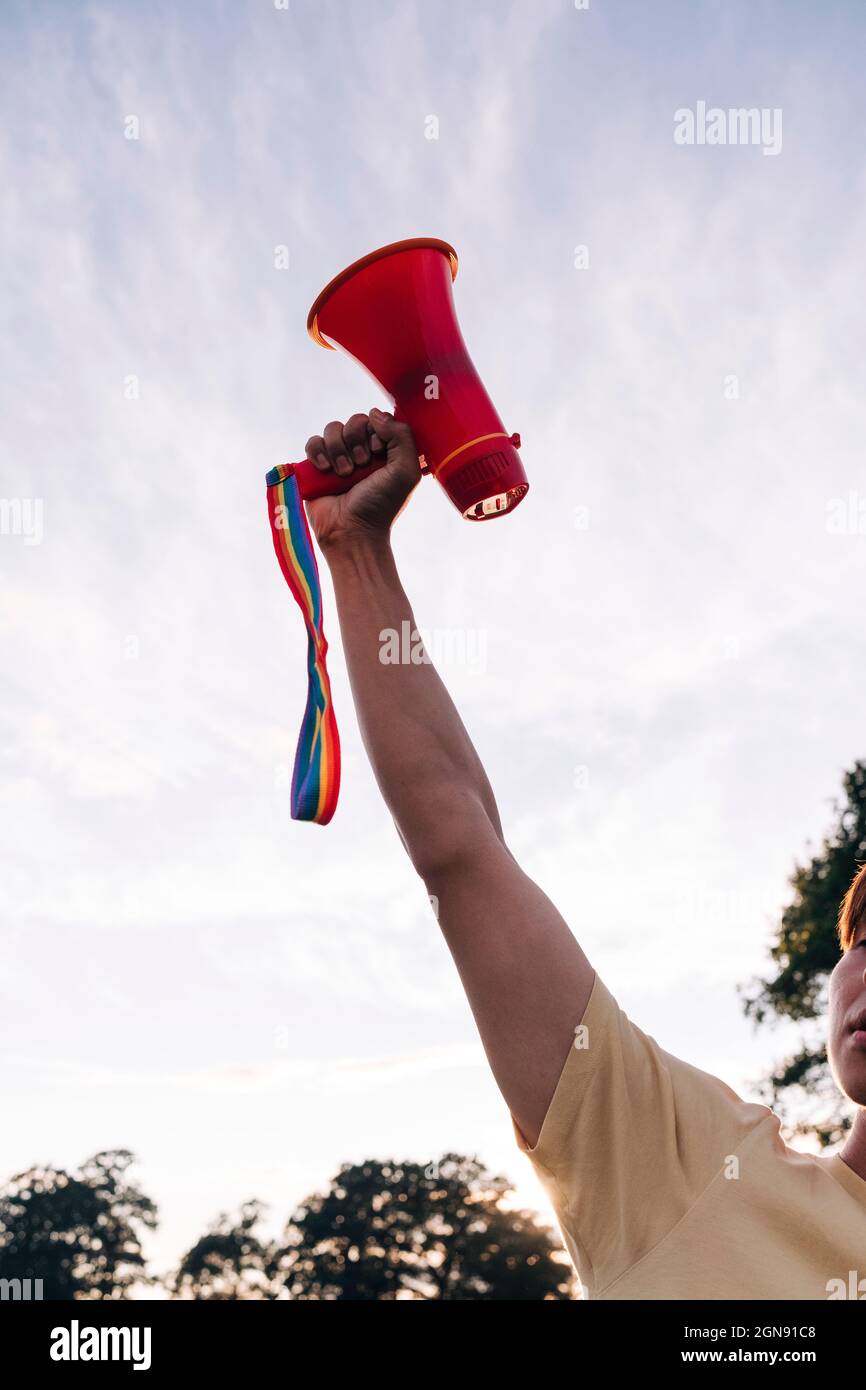 Man with hand raised holding megaphone at park Stock Photo