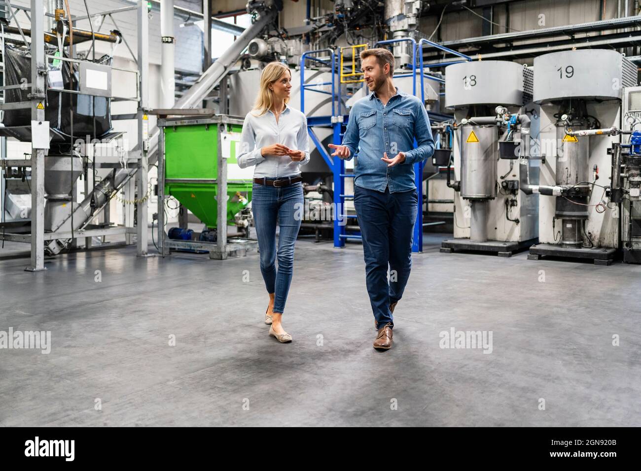 Business professionals discussing while walking in factory Stock Photo