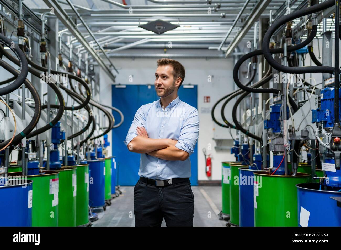 Businessman with arms crossed looking at paint manufacturing machines