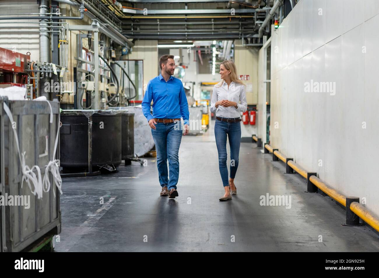 Business professionals discussing while walking in factory Stock Photo