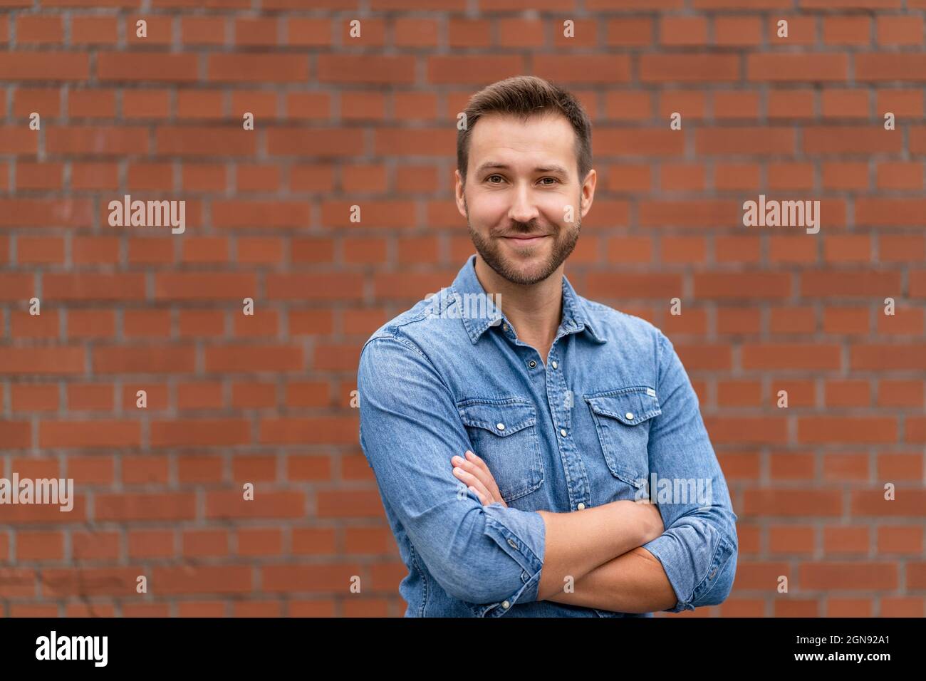 Happy businessman with arms crossed in front of wall Stock Photo - Alamy