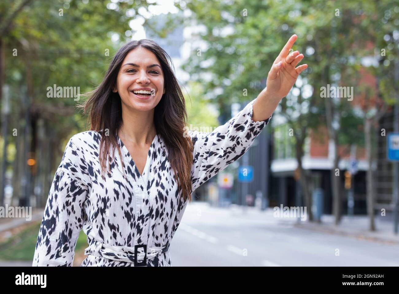 Smiling beautiful young female tourist hailing ride on road Stock Photo