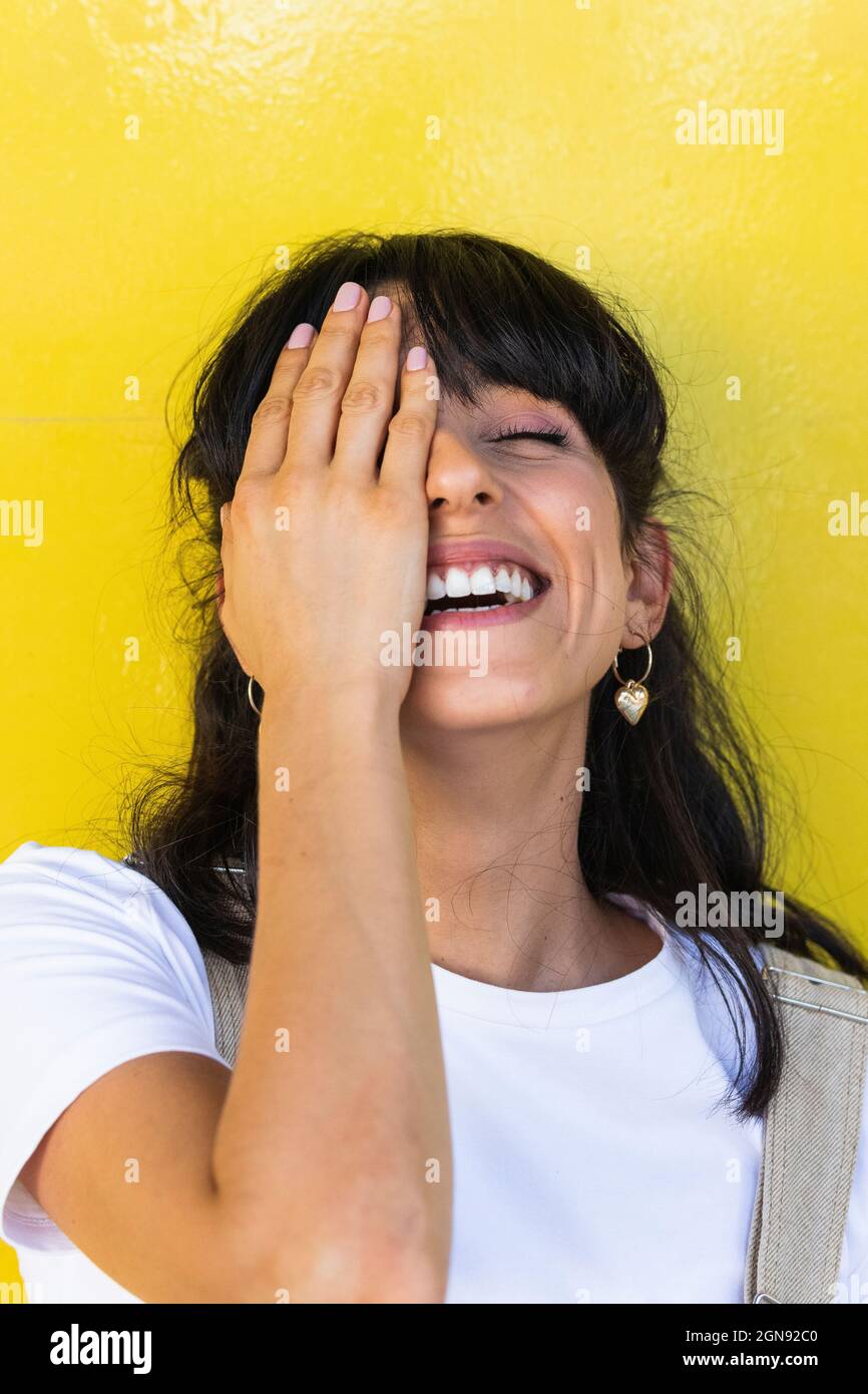Happy woman covering eye with hand Stock Photo