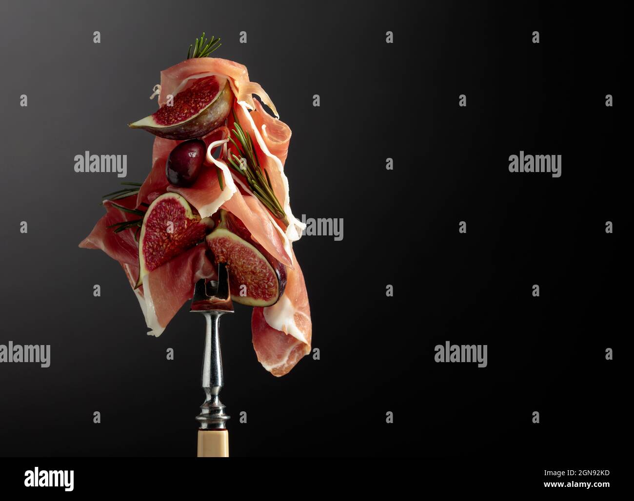 Prosciutto with figs, rosemary, and red olives on a fork. Mediterranean