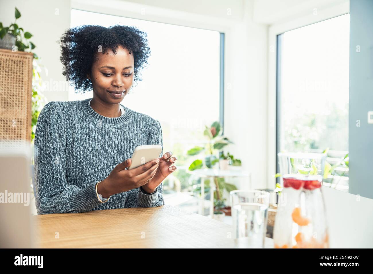Female freelancer using smart phone at home office Stock Photo - Alamy