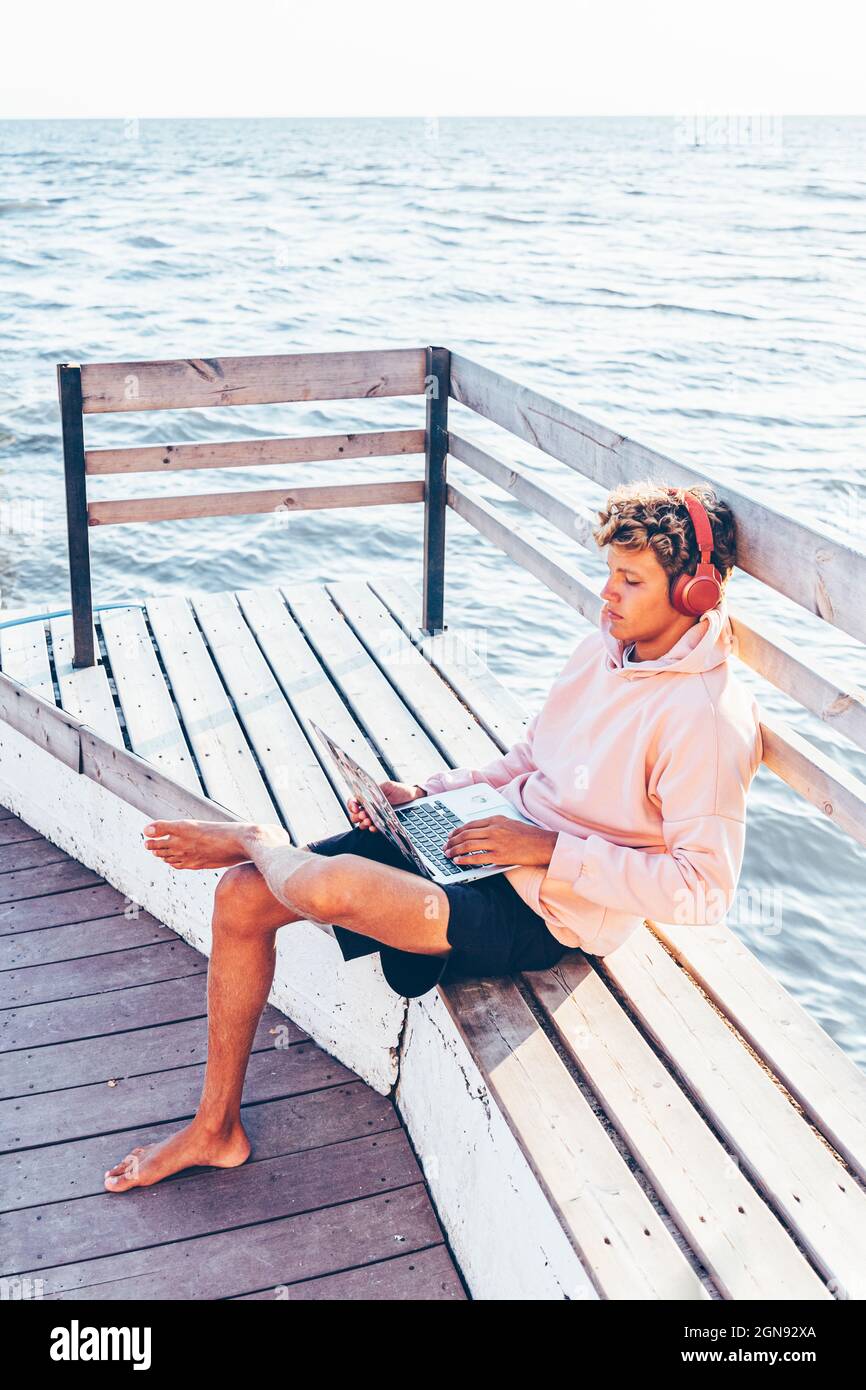 Young man using laptop on bench Stock Photo