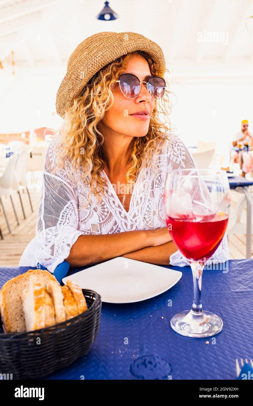 Woman wearing sunglasses sitting with food and drink at table in restaurant Stock Photo