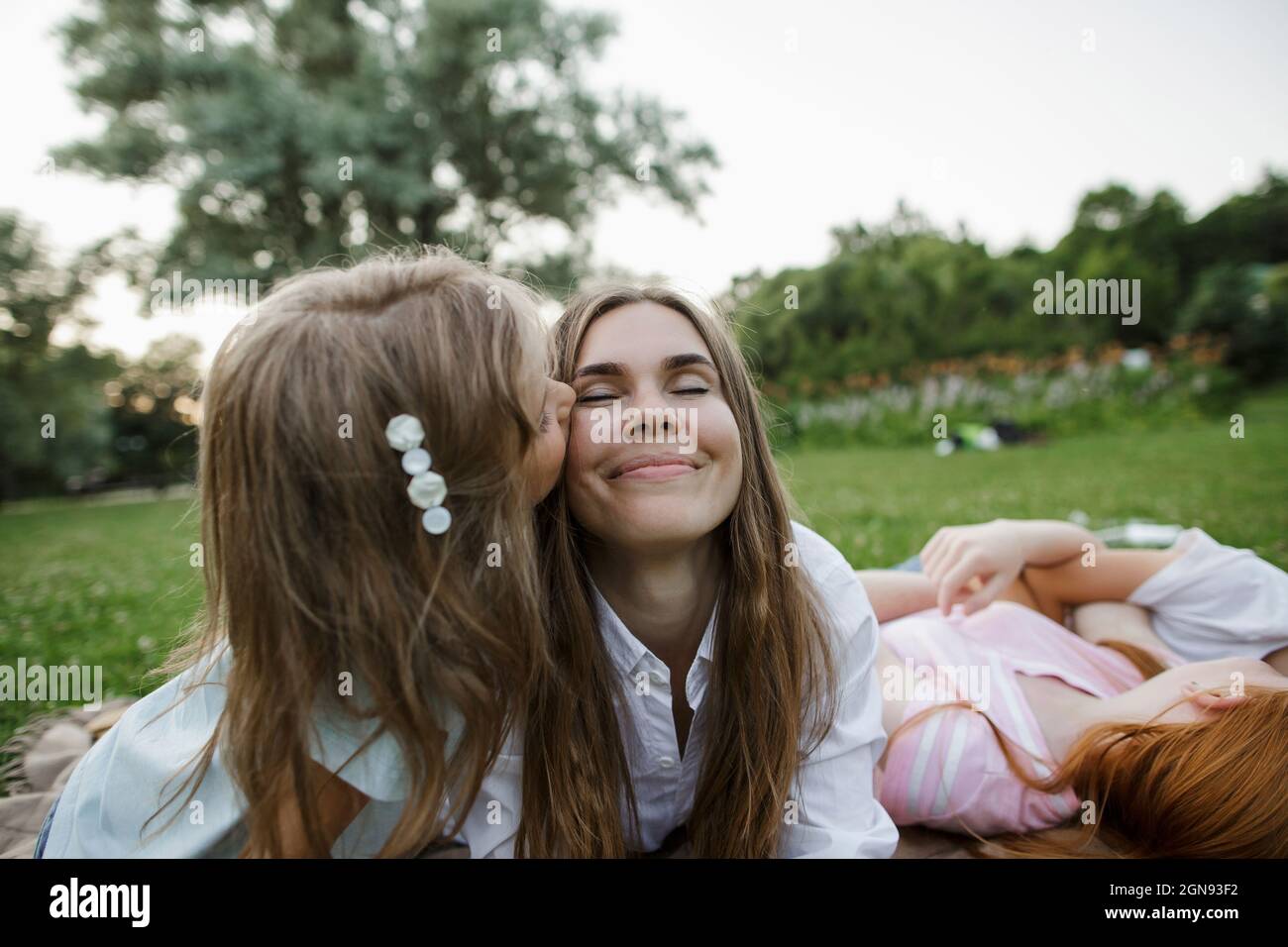 Girl kissing mother at public park Stock Photo