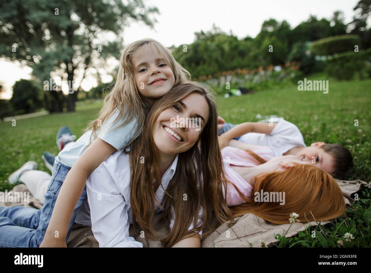 Girl embracing mother by siblings at public park Stock Photo