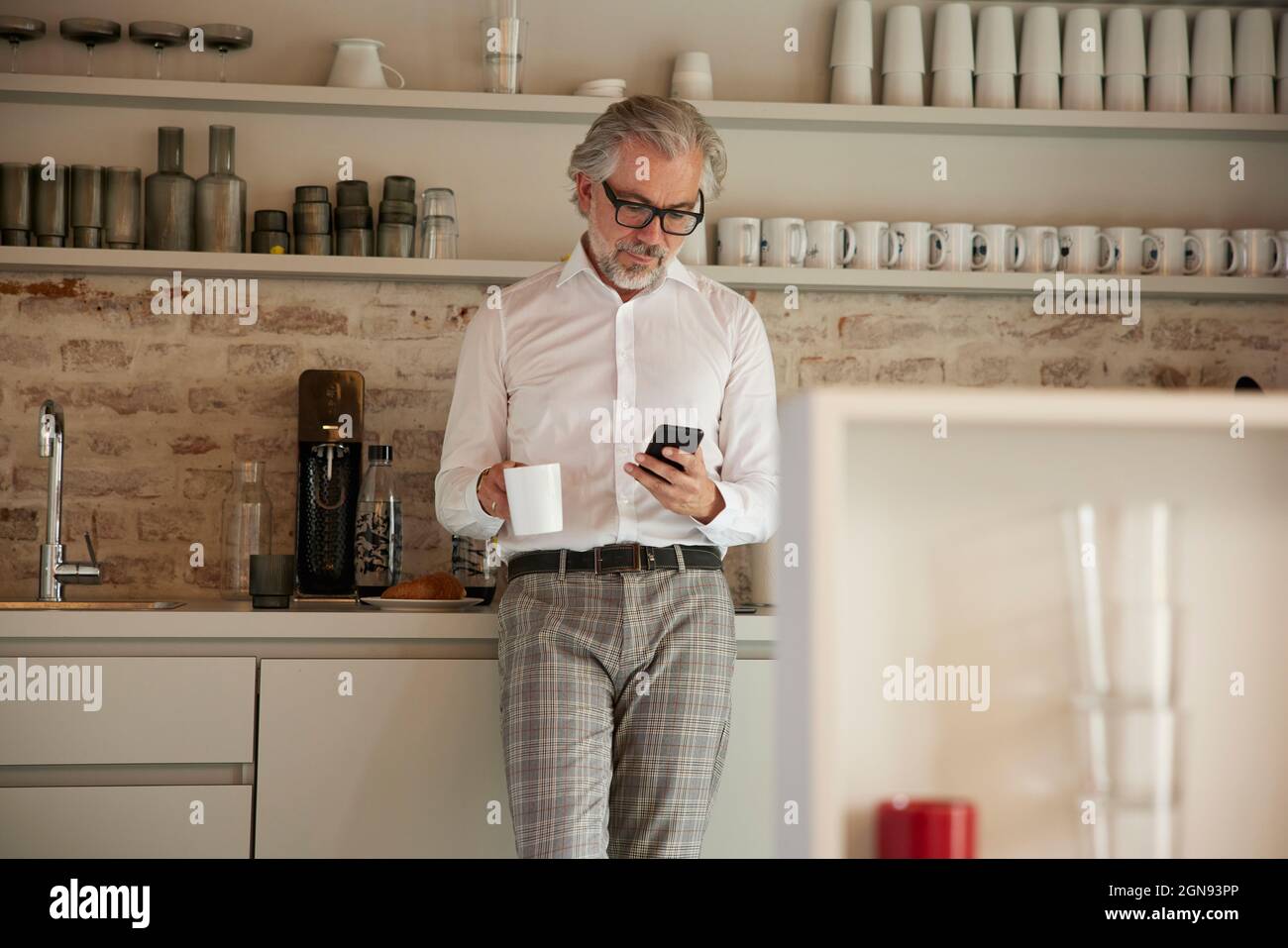 Businessman using mobile phone while having coffee in cafeteria Stock Photo