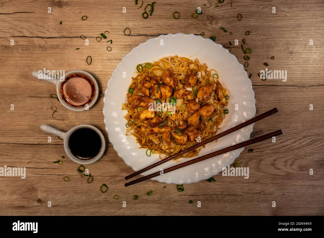 Fried rice noodles with chicken and vegetables served with chili and
