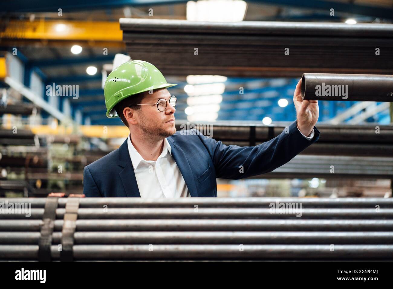 Smiling male professionals measuring pipe with caliper in industry Stock Photo