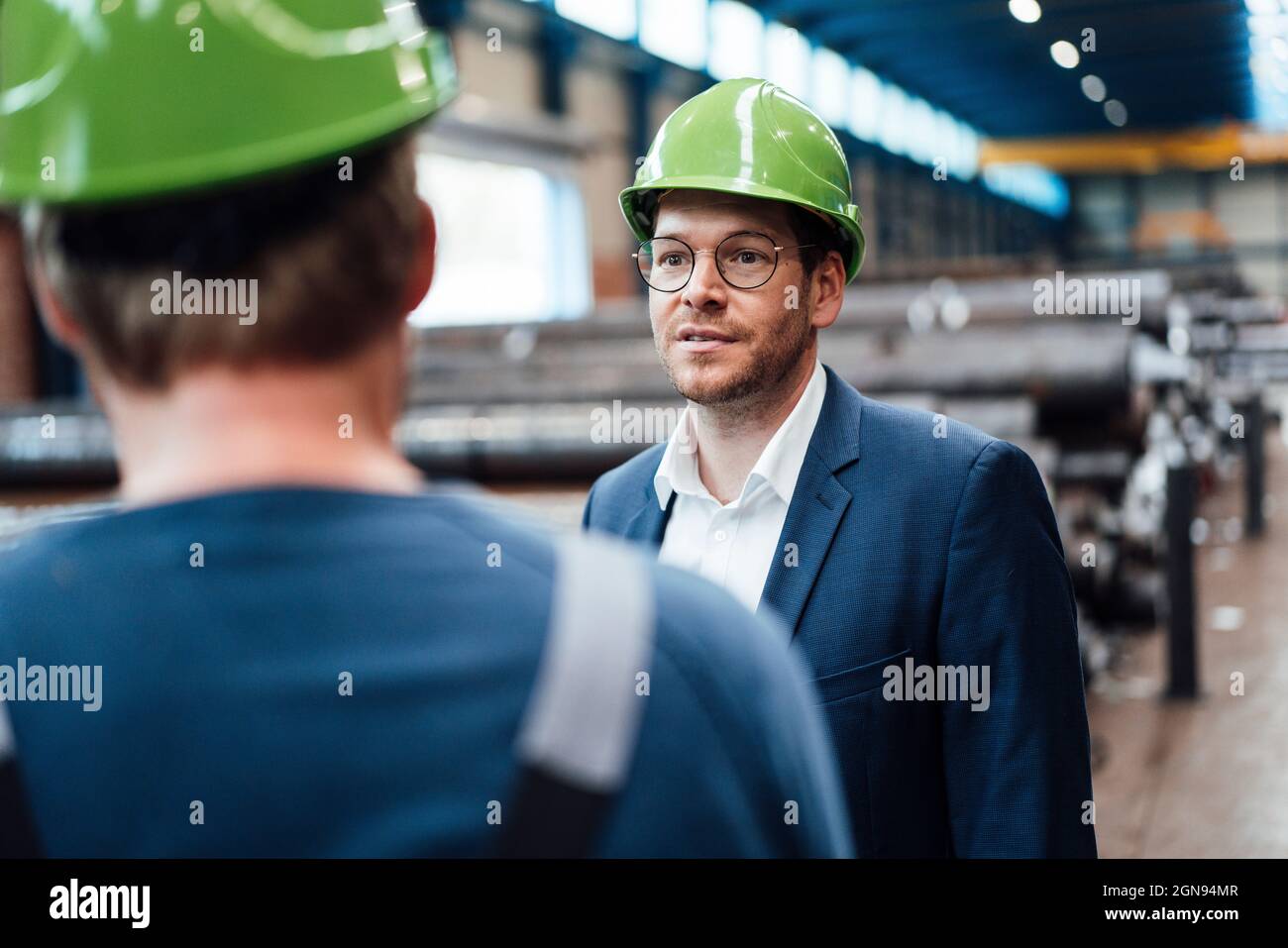 Male warehouse worker discussing with manager in industry Stock Photo