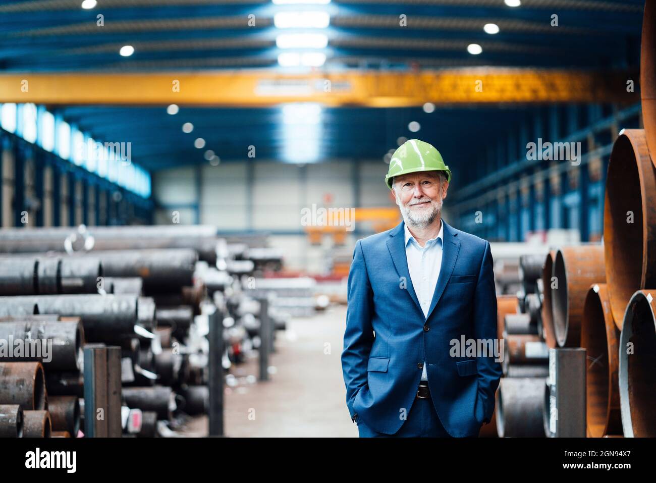 Smiling male manager talking on smart phone in factory Stock Photo