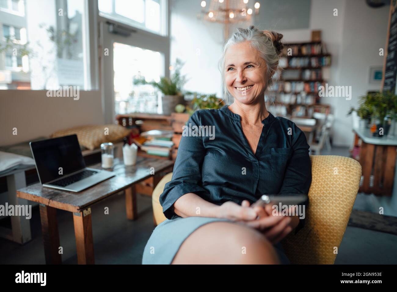 Businesswoman sitting with legs crossed at knee on chair in cafe Stock Photo