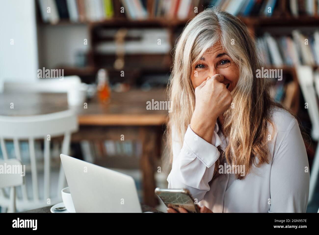 Female freelancer using laptop at table in cafe Stock Photo