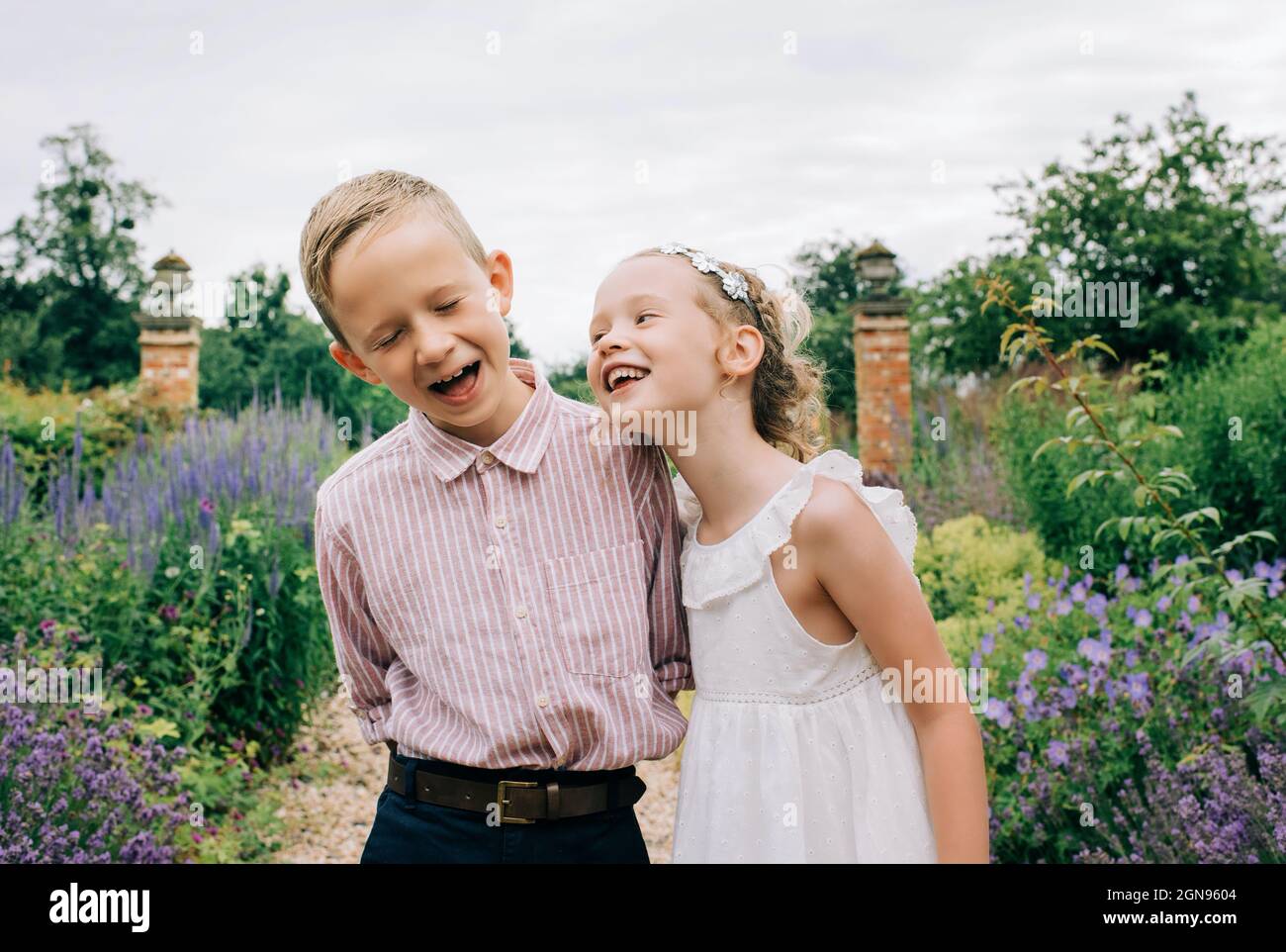 Boy and girl laughing happily in a beautiful flower field Stock Photo