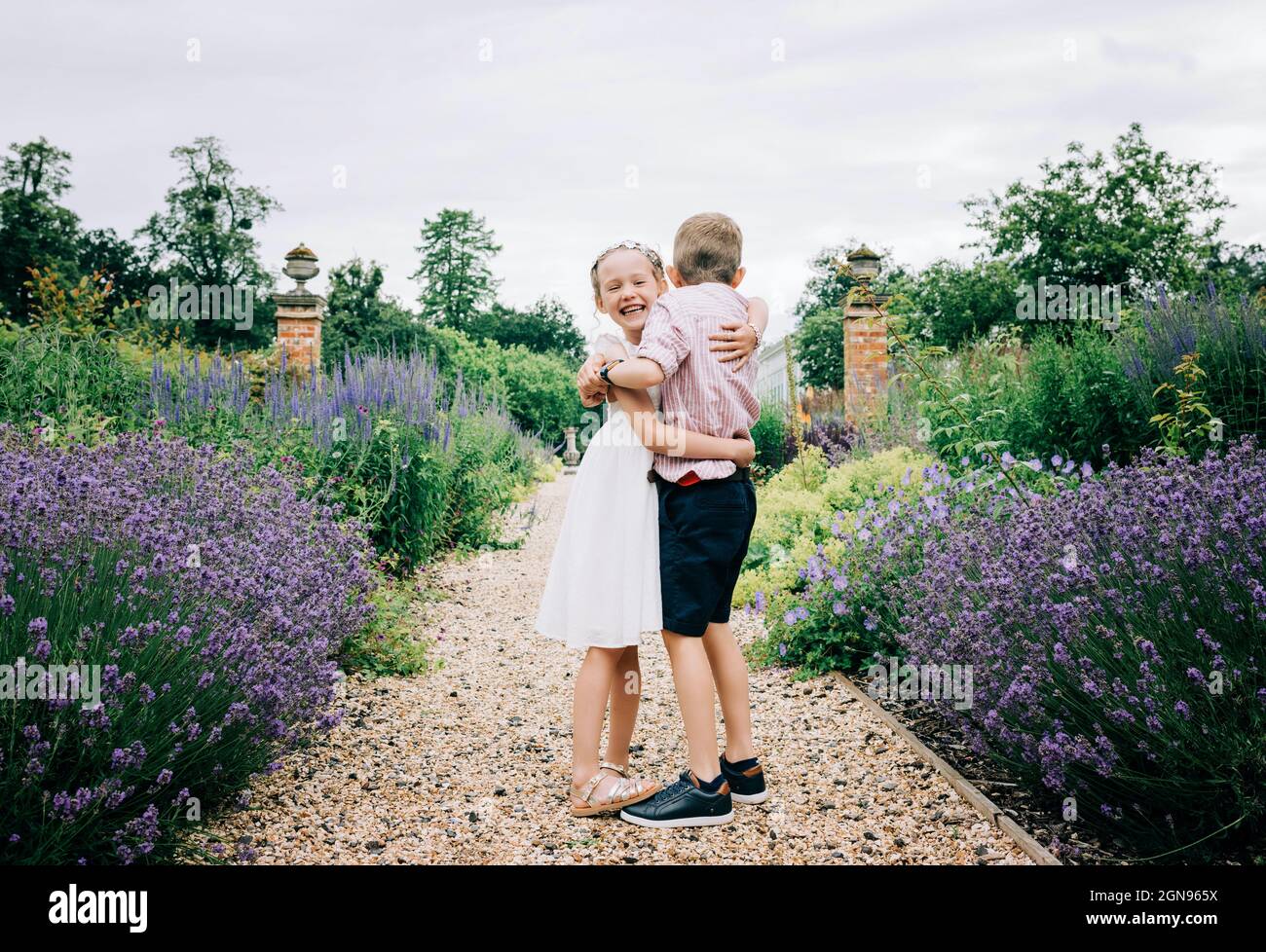 girl and boy hugging and laughing in a beautiful flower field Stock Photo