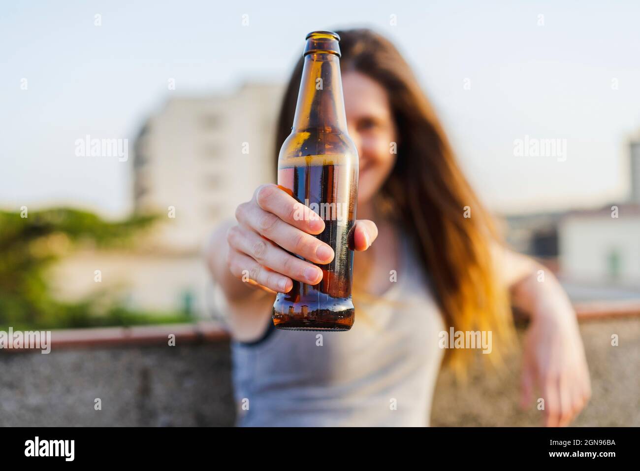 Young woman holding beer bottle at rooftop Stock Photo