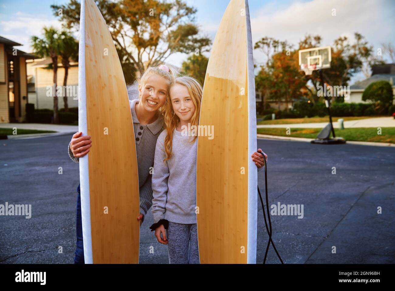 Smiling girls holding surfboards in public park Stock Photo