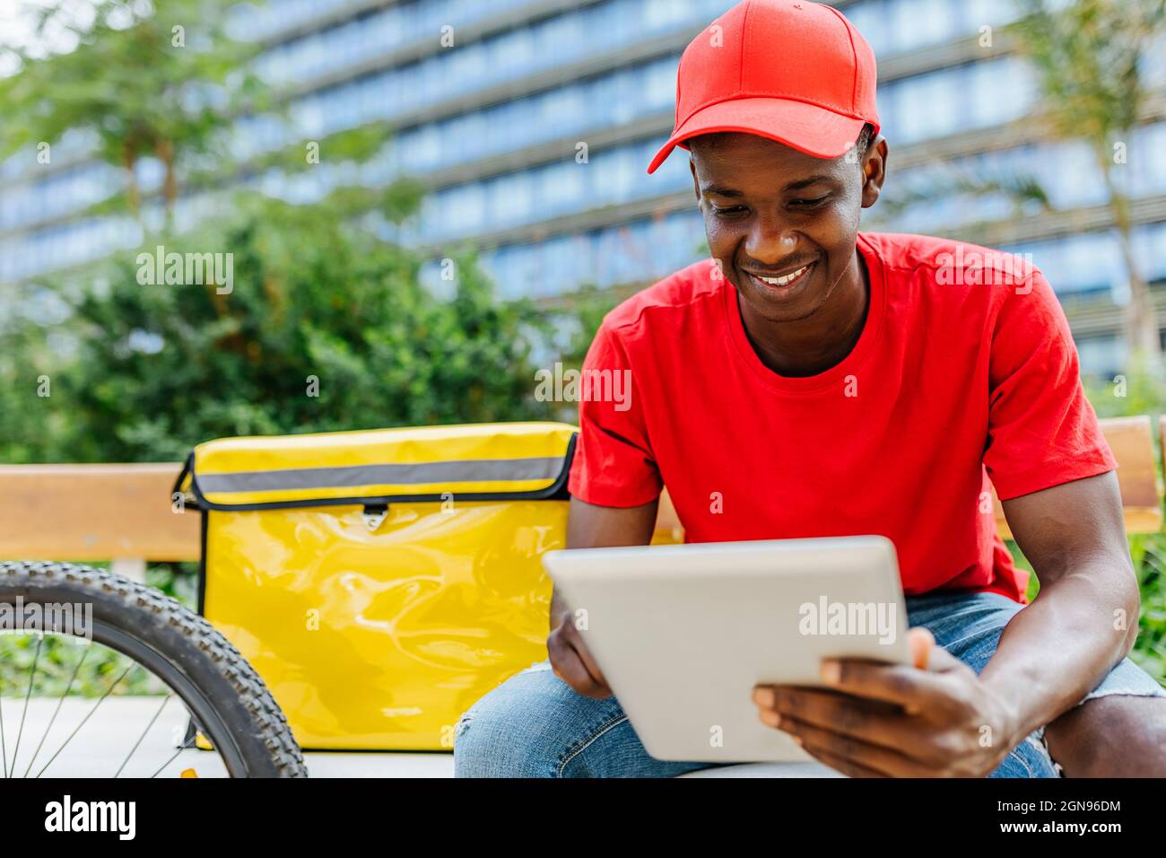 Smiling delivery man using digital tablet on bench Stock Photo