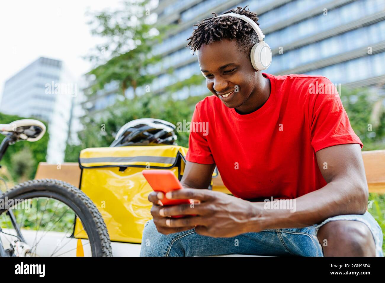 Delivery Man Using Remote Smiling young delivery man using smartphone while listening music ...