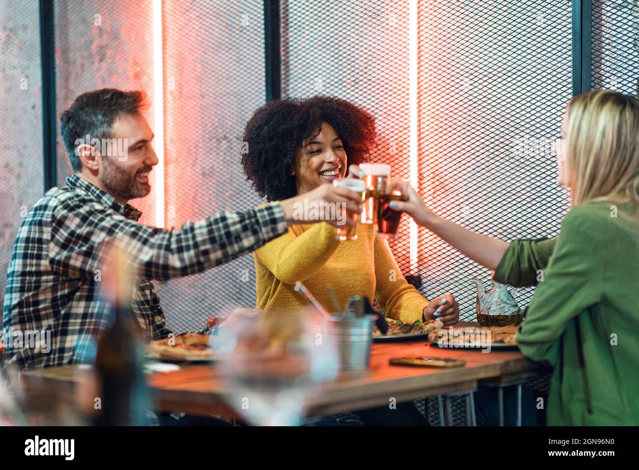 Happy male and female friends raising toasts in restaurant Stock Photo
