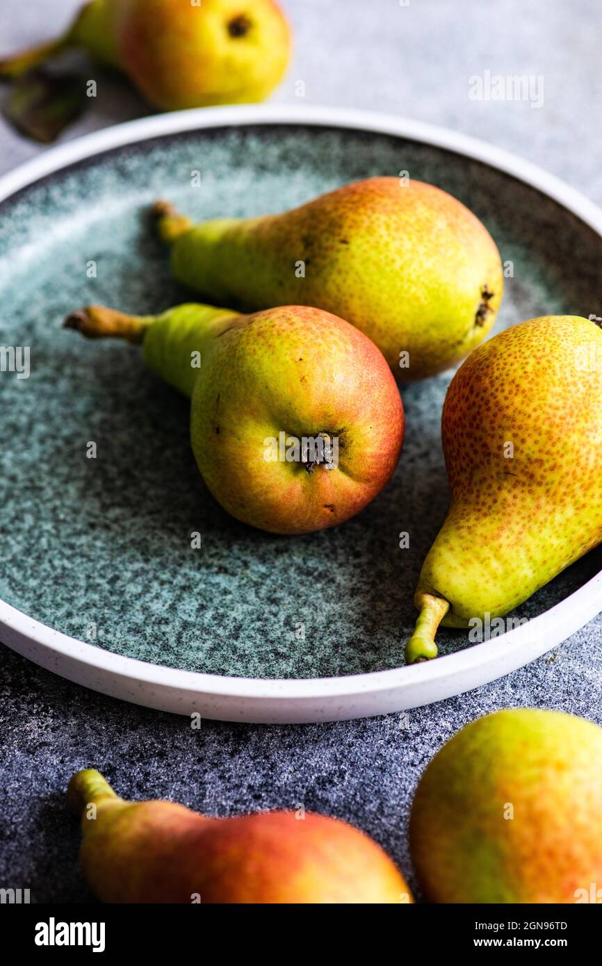 Organic ripe pears in ceramic bowl on rustic table Stock Photo
