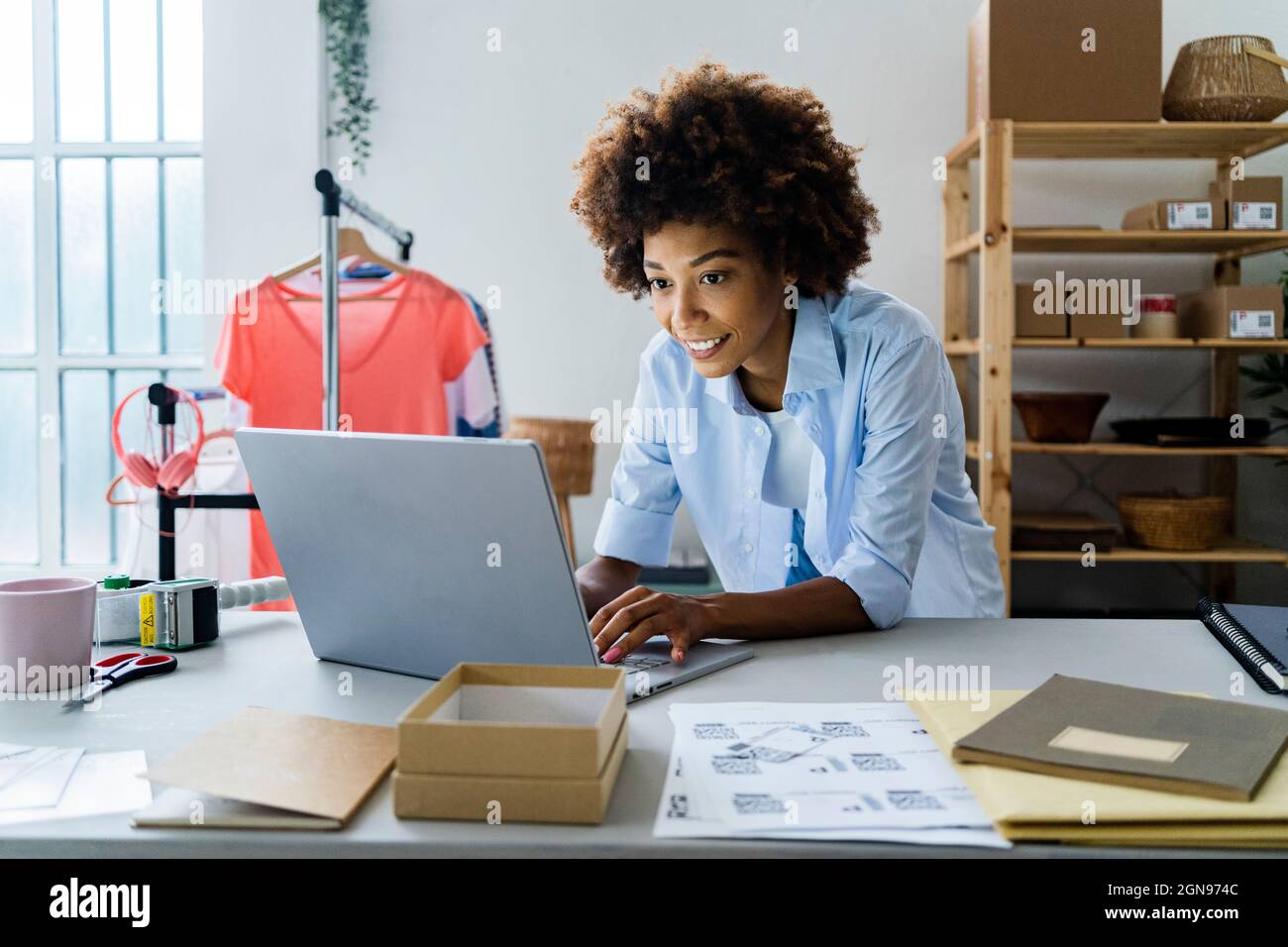 Young female fashion designer using laptop while leaning on desk at studio Stock Photo
