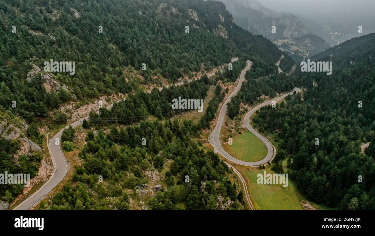 Drone view of country road stretching through forested valley in ...