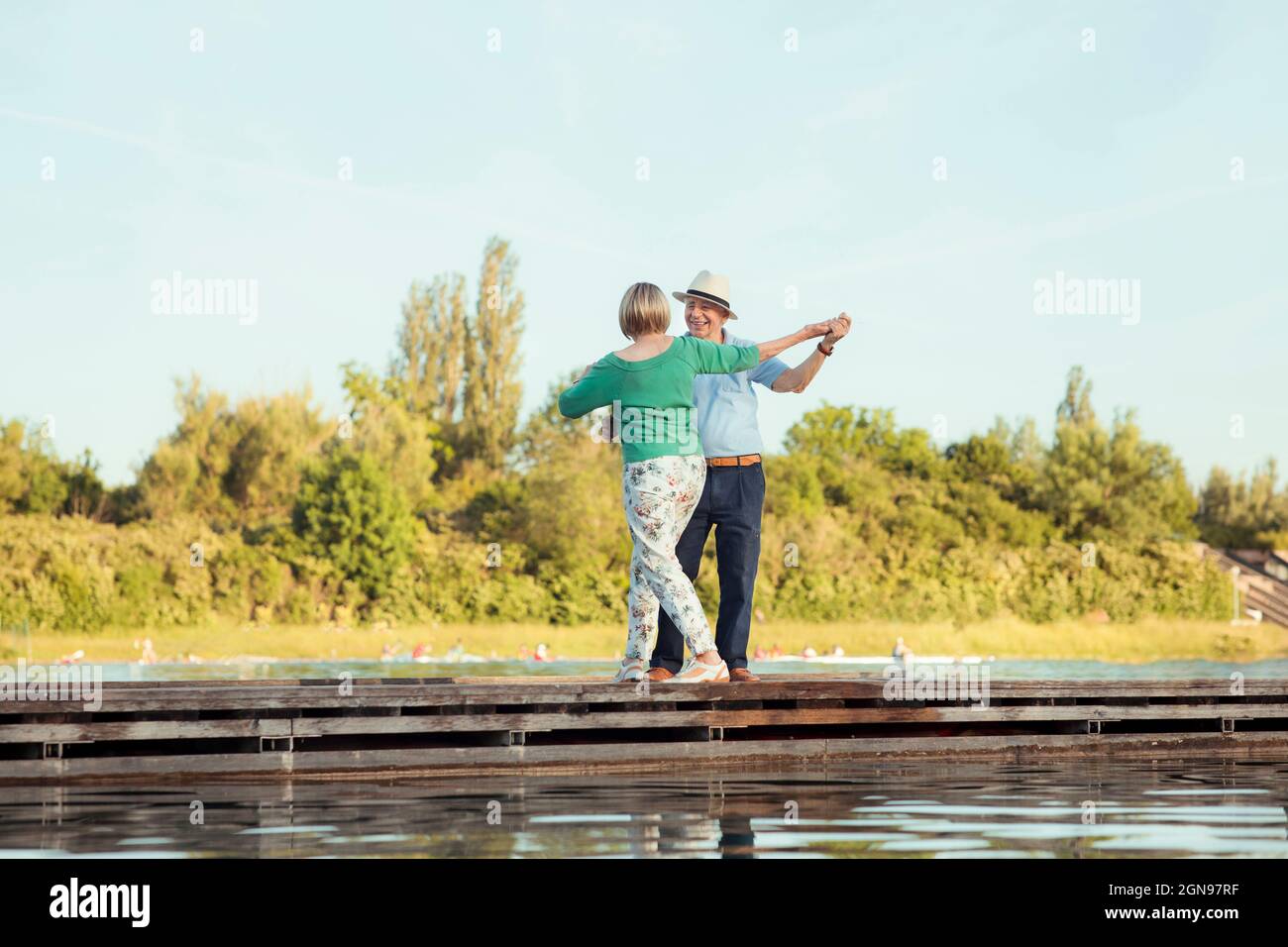 Senior couple holding hands while dancing on jetty Stock Photo