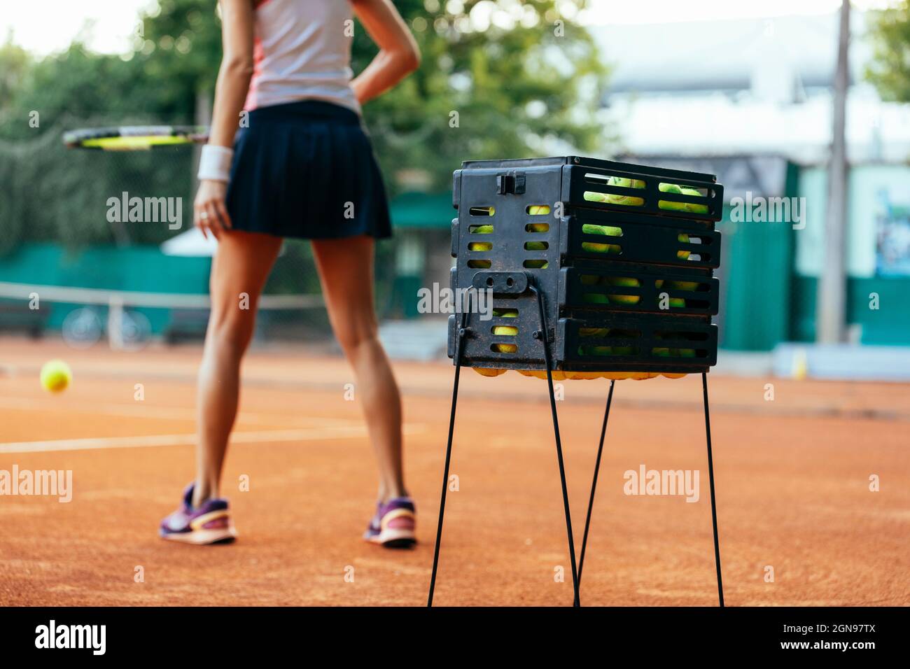 Tennis balls in box with sportswoman practicing in background Stock