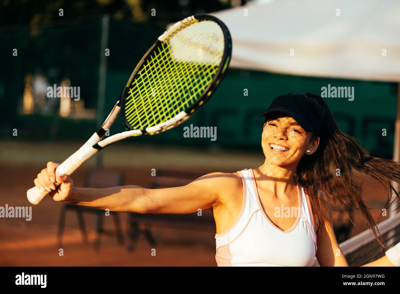 Happy female athlete with racket playing tennis at sports court Stock Photo