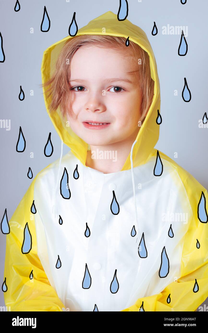 little boy wearing a bright yellow shirt holding a blue umbrella in his hand over a light studio background Stock Photo
