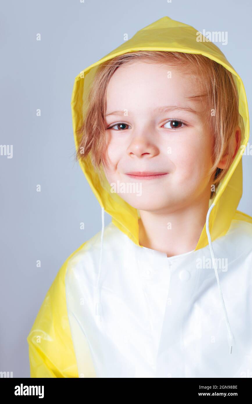 little boy wearing a bright yellow shirt holding a blue umbrella in his hand over a light studio background Stock Photo
