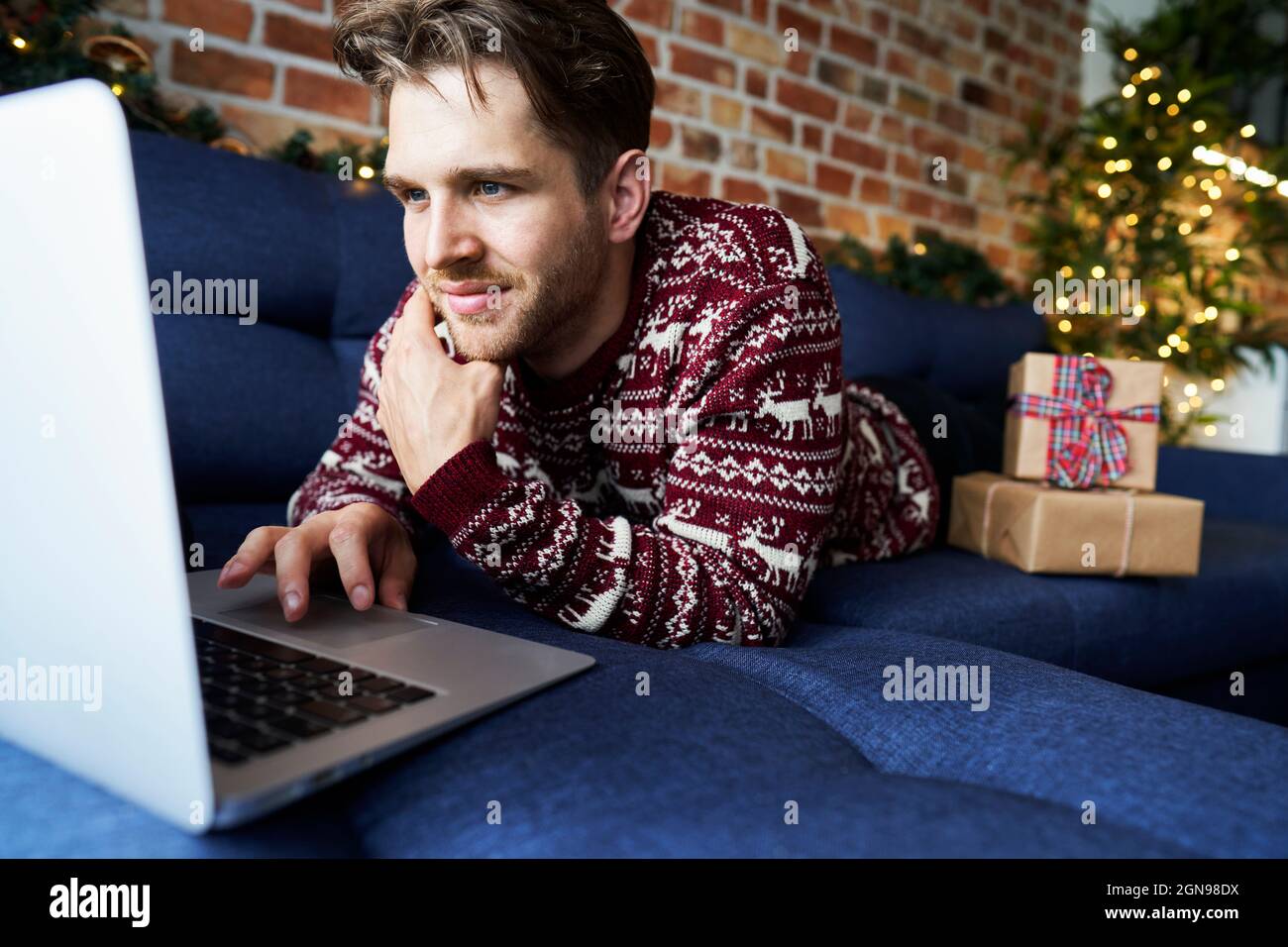 Young man using laptop while relaxing on sofa Stock Photo