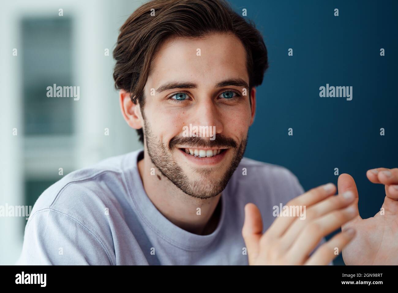 Smiling young man gesturing at home Stock Photo