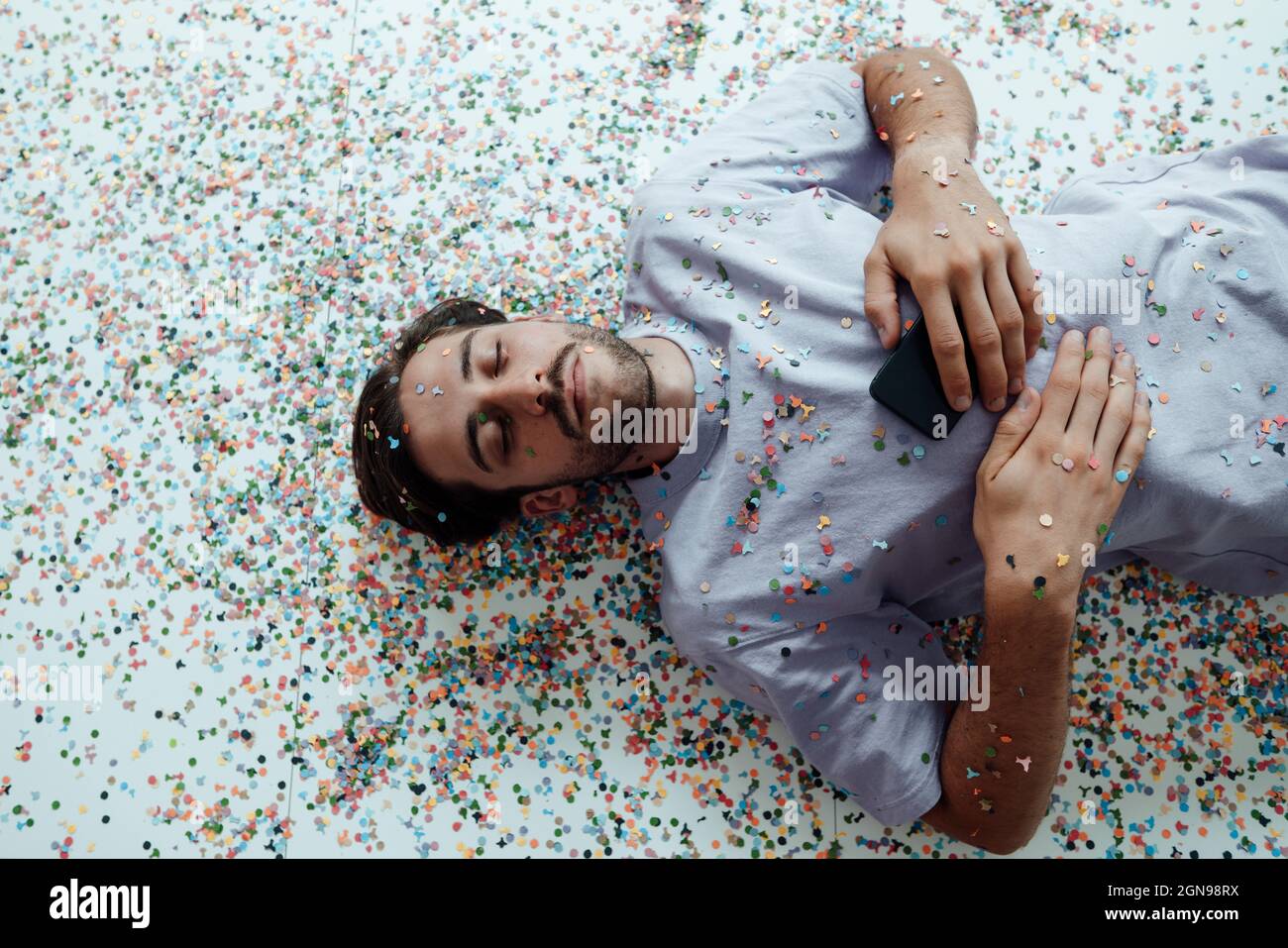 Young man relaxing on floor with confetti Stock Photo