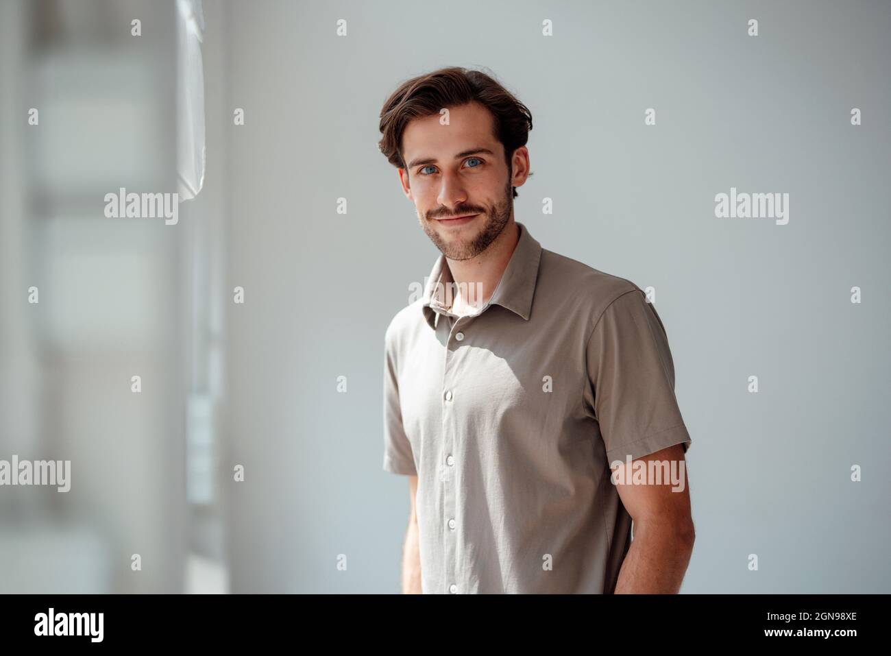 Smiling young man standing at home Stock Photo