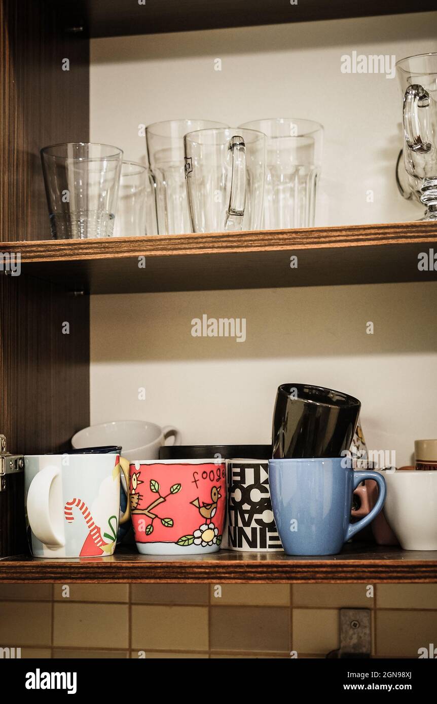 Open wooden cupboard with cups and glass Stock Photo Alamy