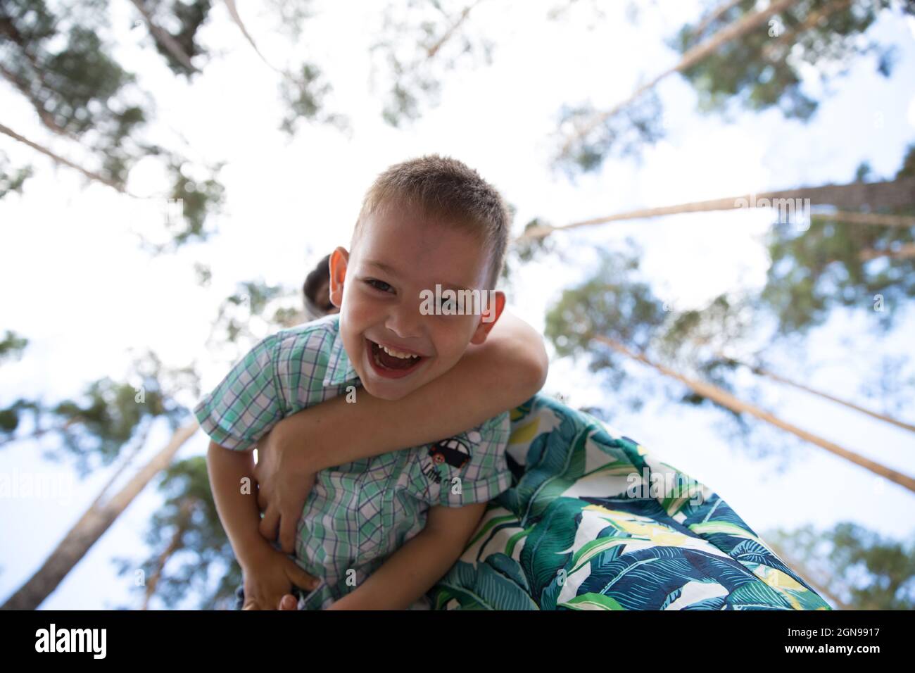 a boy laughs in his mother's arms in the park Stock Photo