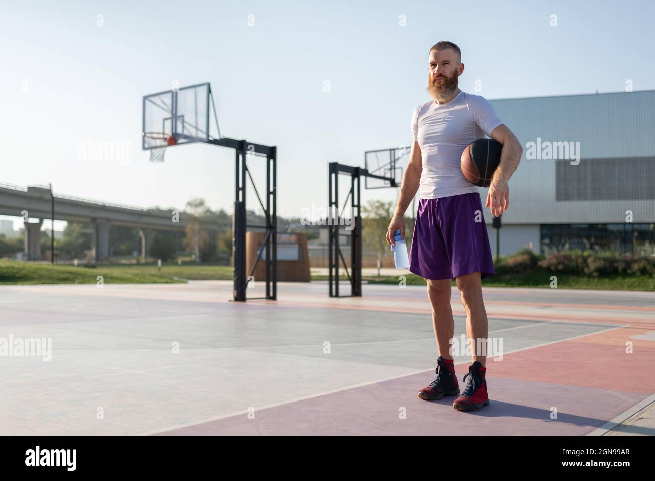 Sportsman with bottle and ball standing on streetball court during training Stock Photo
