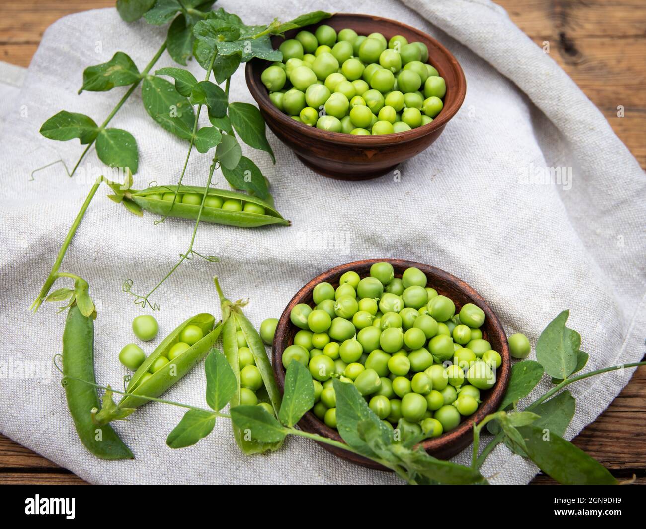 Fresh green peas young in bowl, on wood table, top view, seeds, pods, sprouts. Stock Photo
