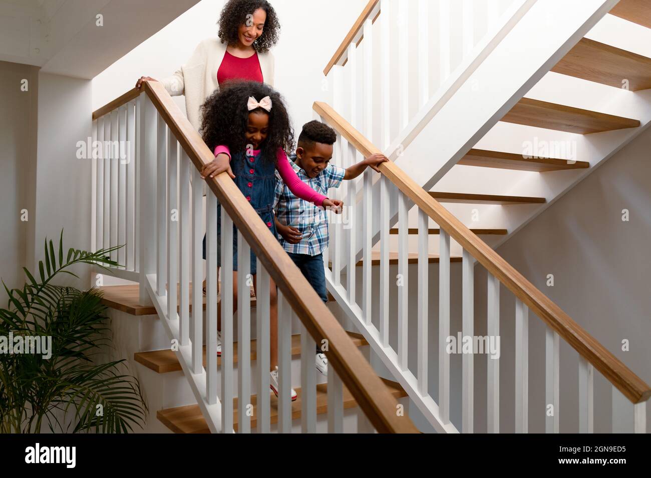 Happy african american mother and children walking downstairs Stock Photo